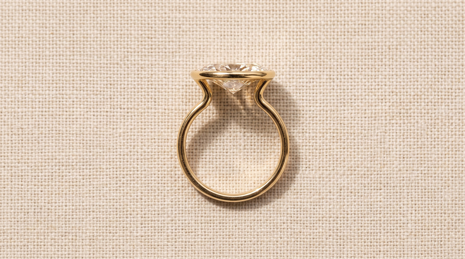 An East-West Bezel Oval engagement ring by MARLII LAB, shown in side profile with the MARLII Cutaway open beneath the stone
