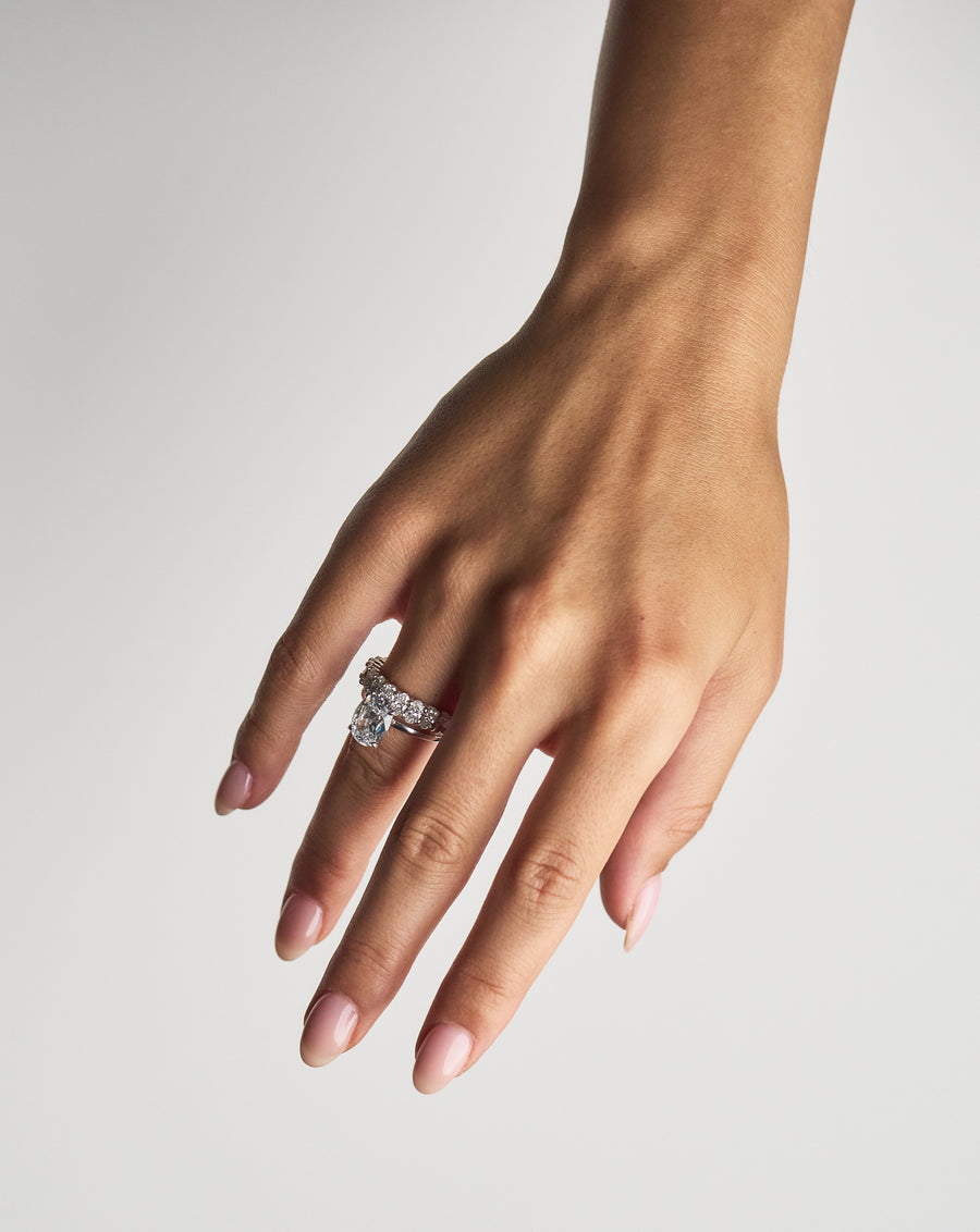 Claw-Set Oval Band Grand in 18K yellow gold, worn on the hand beside an engagement ring
