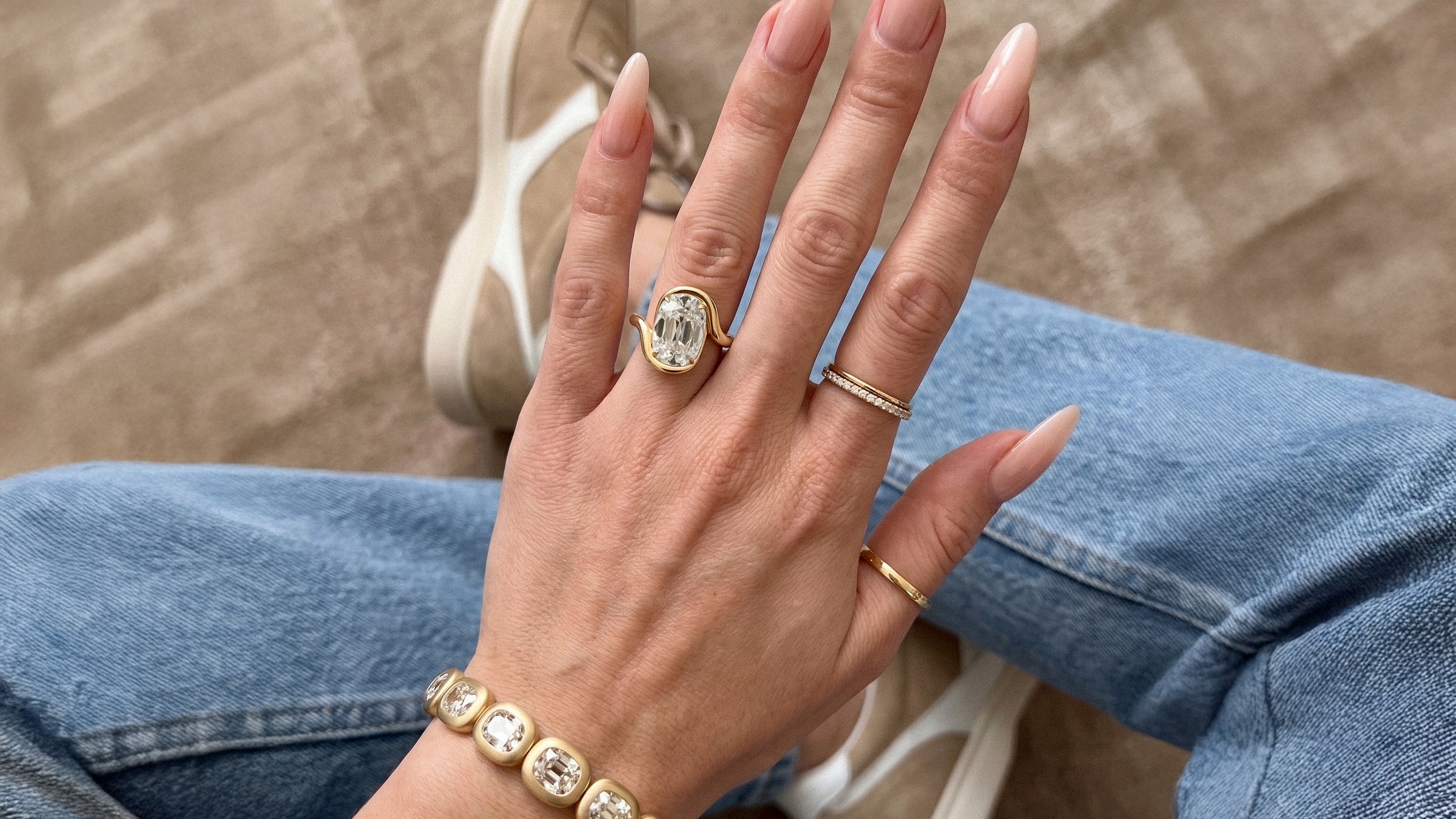 A MARLII LAB sculptural engagement ring worn with a diamond bracelet, photographed in daylight